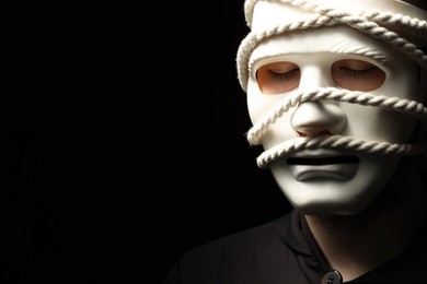 Photo of Theatrical performance. Man with plastic mask and hemp rope on black background, space for text