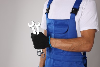 Photo of Auto mechanic with wrenches on light grey background, closeup. Space for text