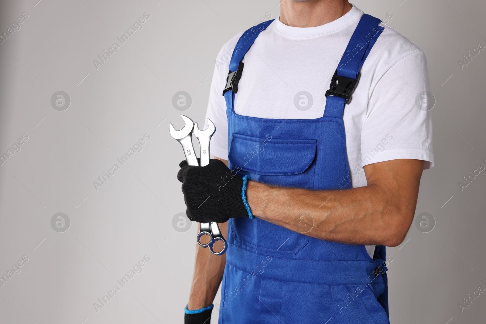 Photo of Auto mechanic with wrenches on light grey background, closeup. Space for text