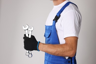 Photo of Auto mechanic with wrenches on light grey background, closeup