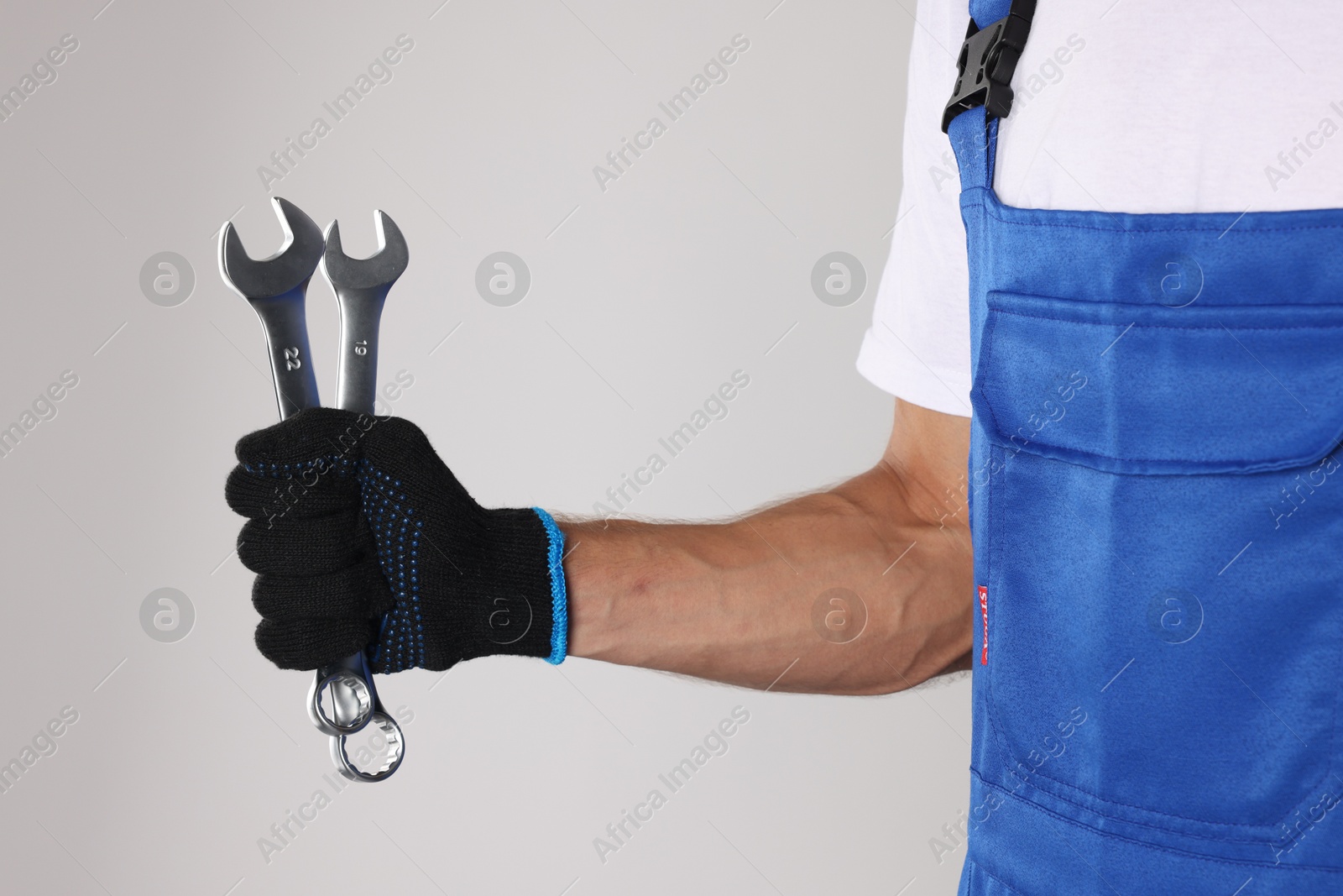 Photo of Auto mechanic with wrenches on light grey background, closeup