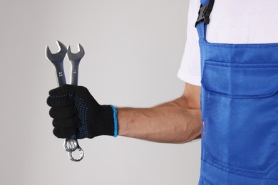 Photo of Auto mechanic with wrenches on light grey background, closeup