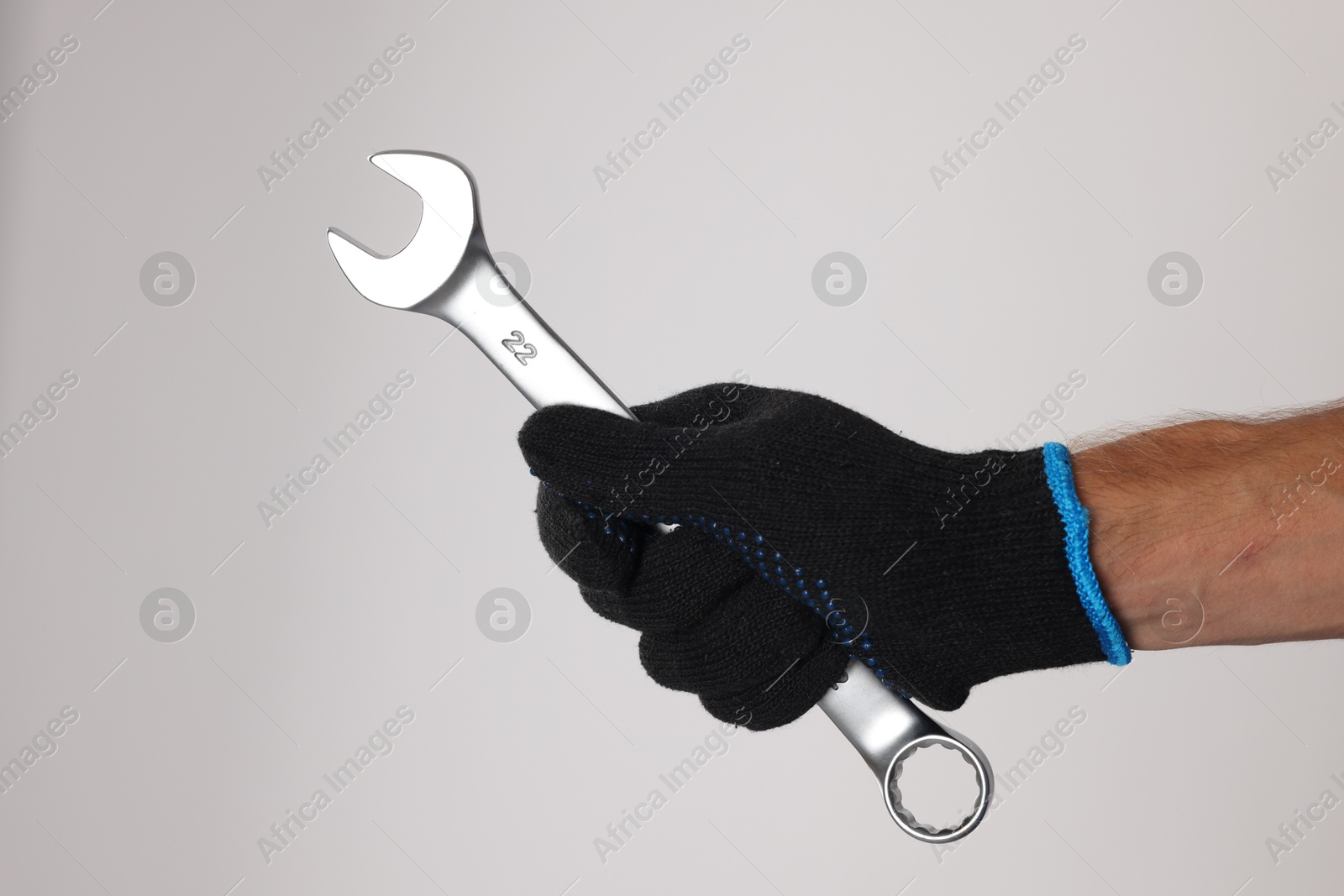 Photo of Auto mechanic with wrench on light grey background, closeup