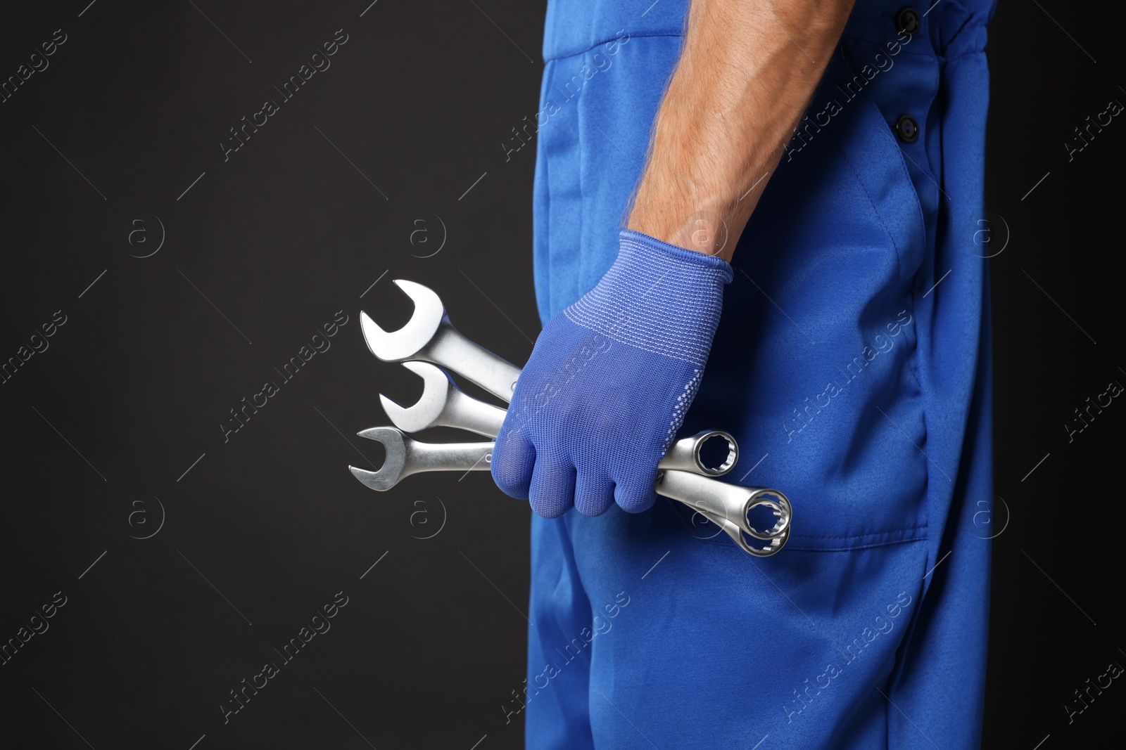 Photo of Auto mechanic with wrenches on black background, closeup. Space for text