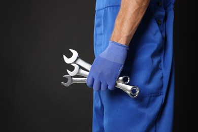 Photo of Auto mechanic with wrenches on black background, closeup. Space for text