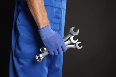 Auto mechanic with wrenches on black background, closeup. Space for text