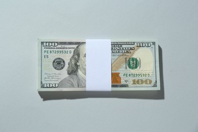 Bundle of dollar banknotes on light grey background, top view