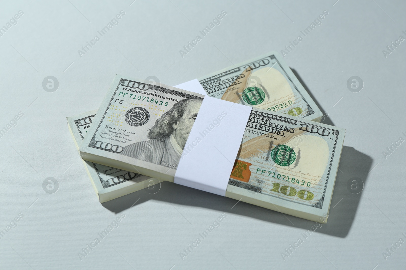 Photo of Bundles of dollar banknotes on light grey background