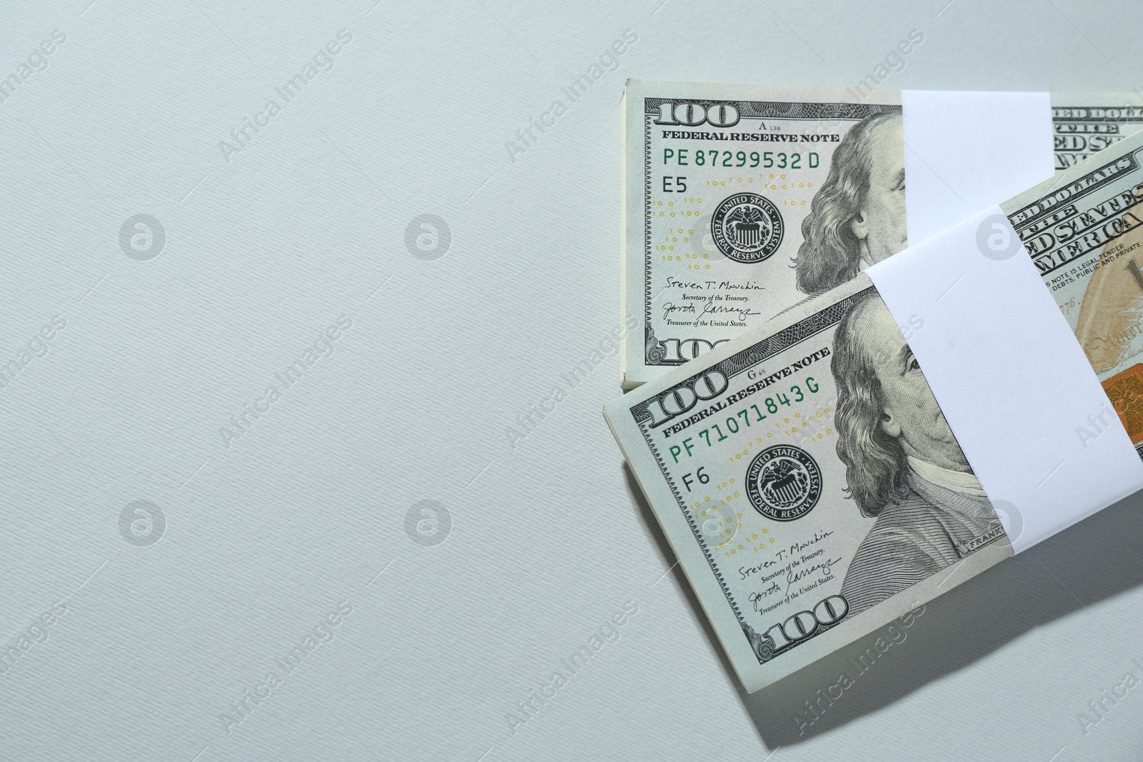 Photo of Bundles of dollar banknotes on light grey background, top view. Space for text