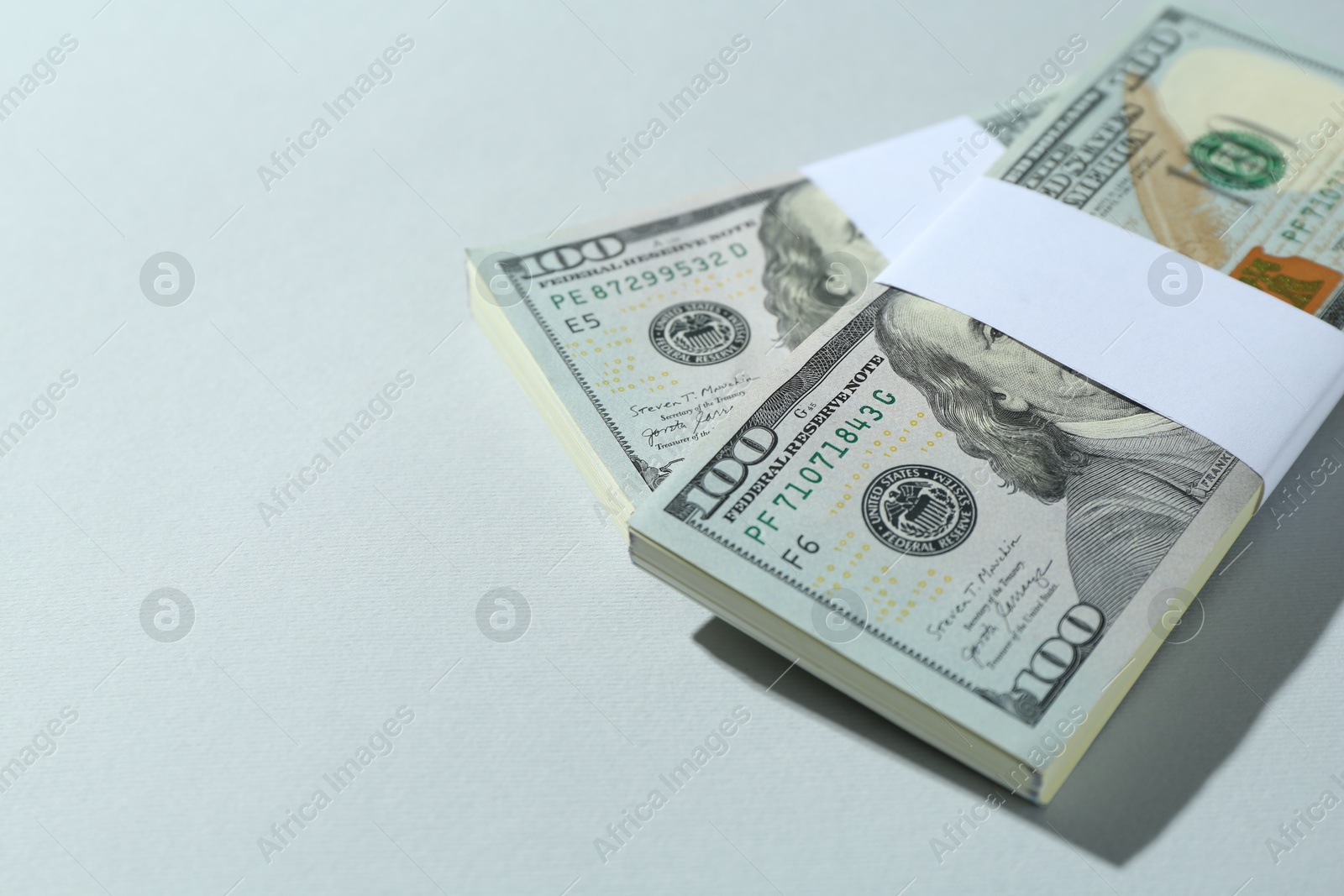 Photo of Bundles of dollar banknotes on light grey background, closeup. Space for text