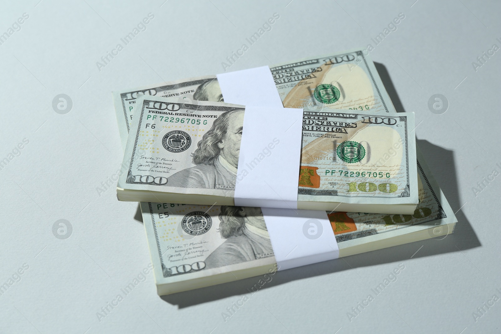 Photo of Bundles of dollar banknotes on light grey background