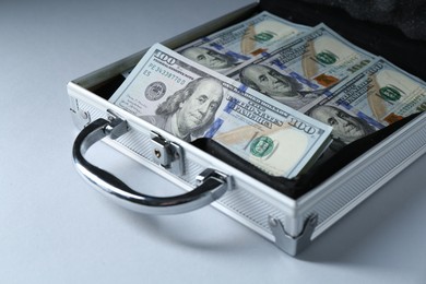 Metal case full of dollar banknotes on light background