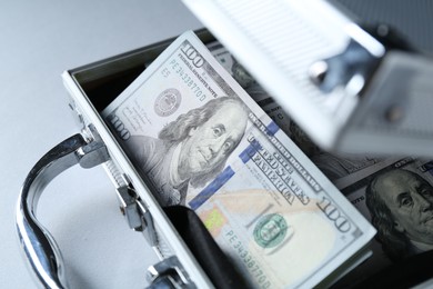 Photo of Metal case full of dollar banknotes on light background, closeup