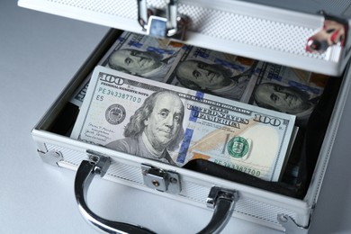 Metal case full of dollar banknotes on light background