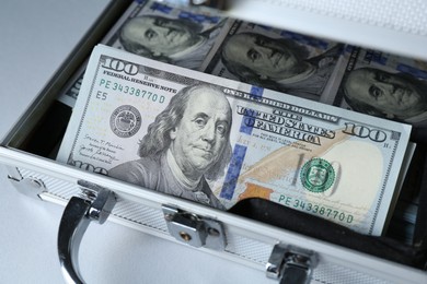 Photo of Metal case full of dollar banknotes on light background, closeup