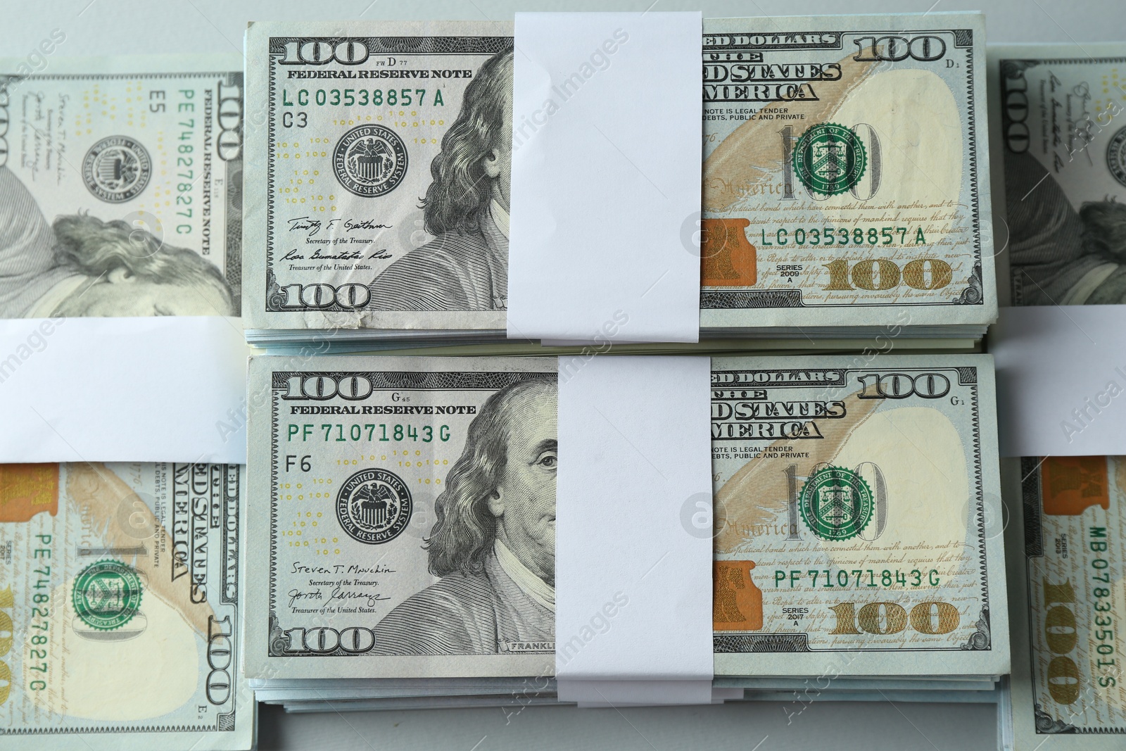 Photo of Bundles of dollar banknotes on light grey background, top view