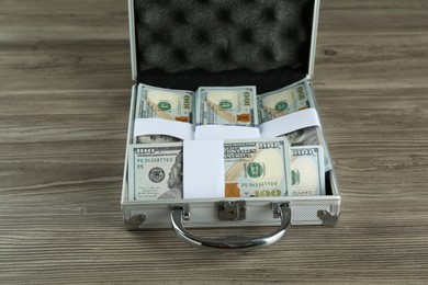 Metal case full of dollar banknotes at wooden table