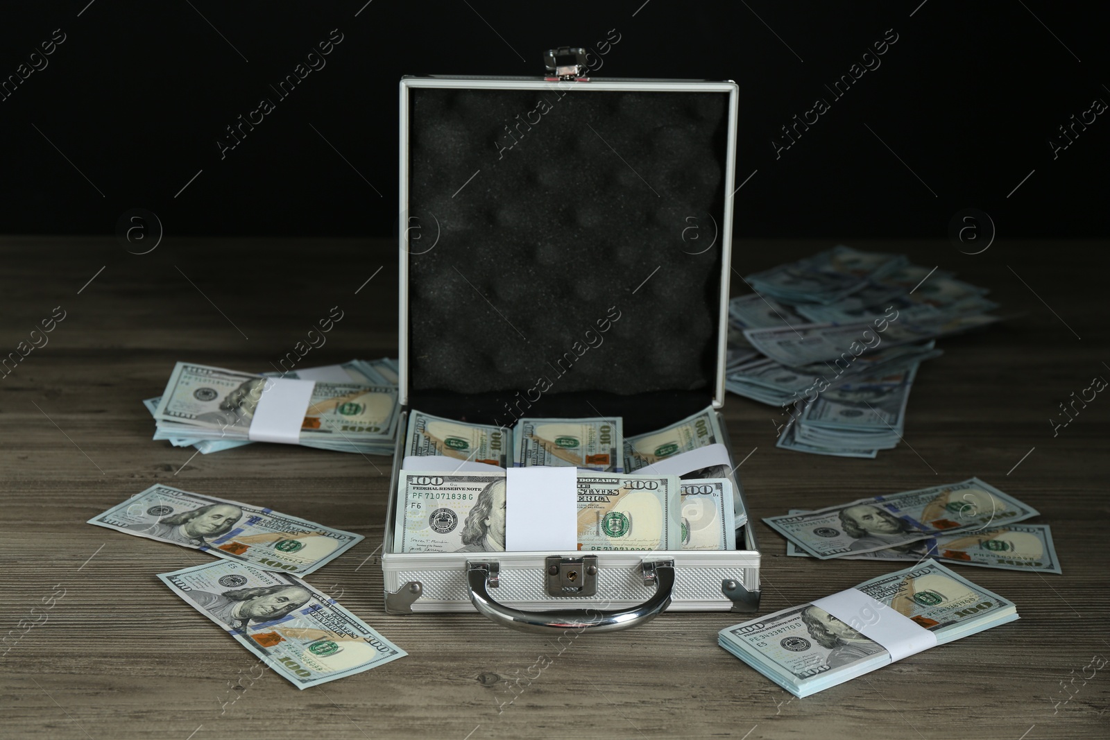 Photo of Metal case with dollar banknotes on wooden table