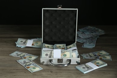 Metal case with dollar banknotes on wooden table