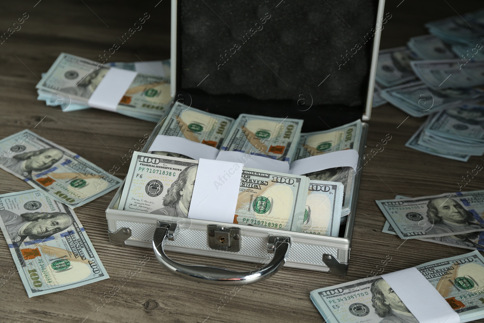 Photo of Metal case with dollar banknotes on wooden table