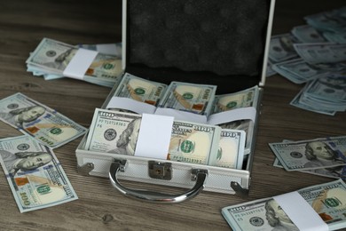 Metal case with dollar banknotes on wooden table