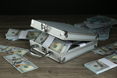 Metal case with dollar banknotes on wooden table