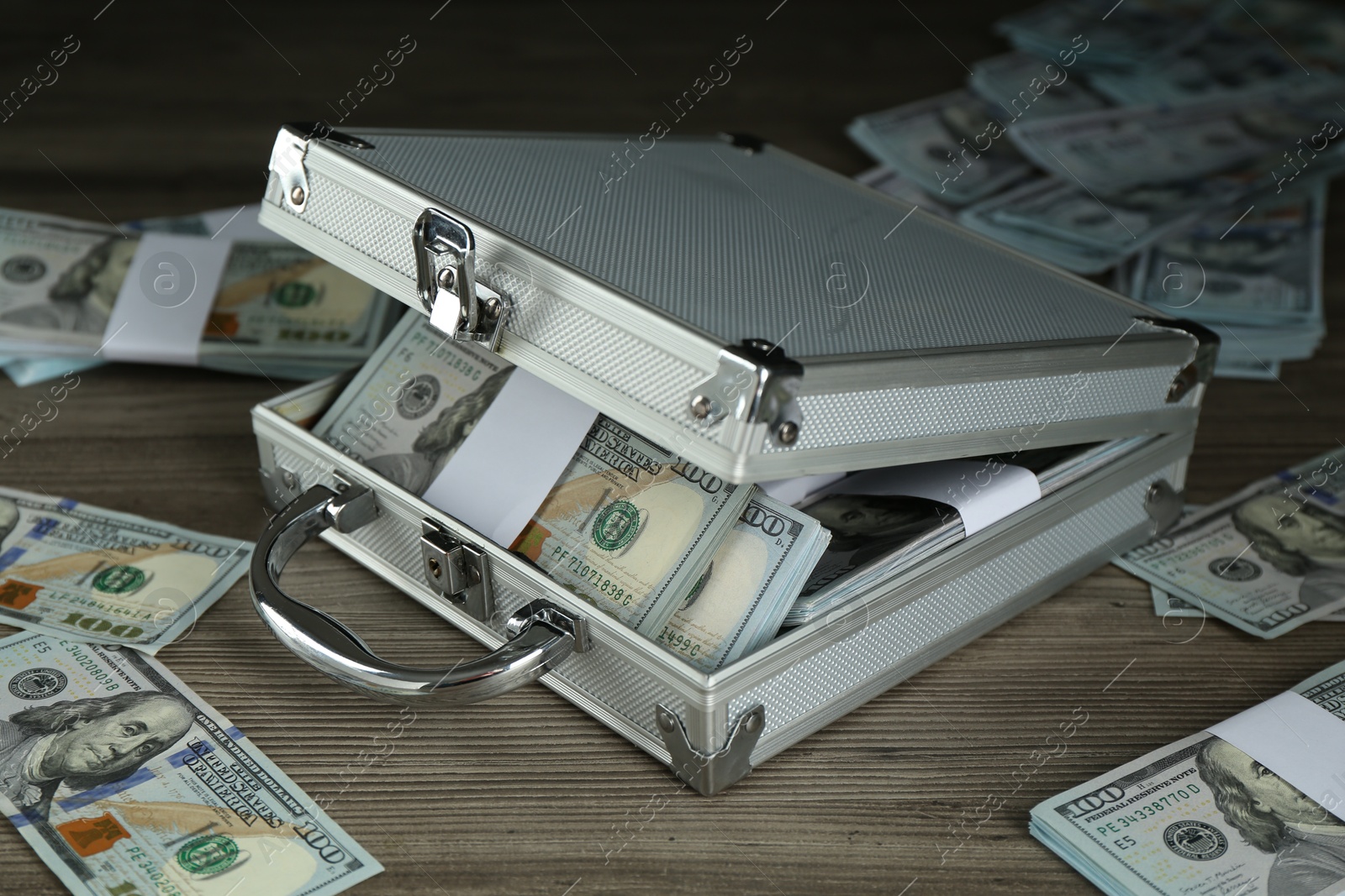 Photo of Metal case with dollar banknotes on wooden table