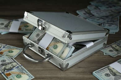 Metal case with dollar banknotes on wooden table