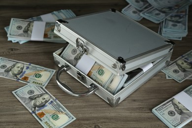 Photo of Metal case with dollar banknotes on wooden table