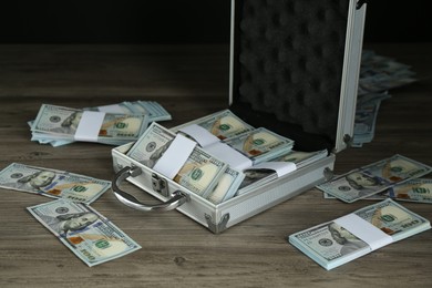 Metal case with dollar banknotes on wooden table