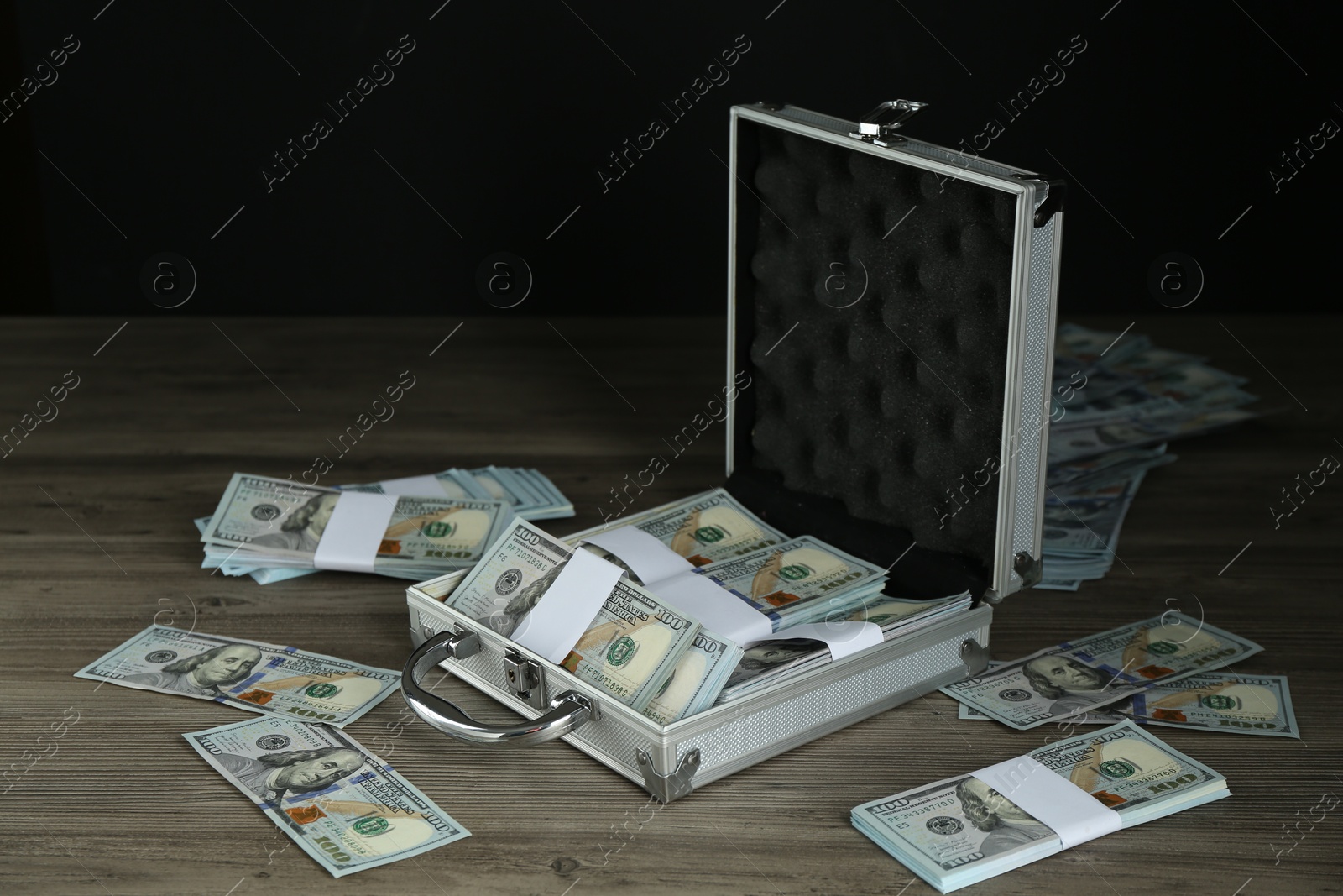 Photo of Metal case with dollar banknotes on wooden table