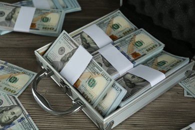 Metal case with dollar banknotes on wooden table