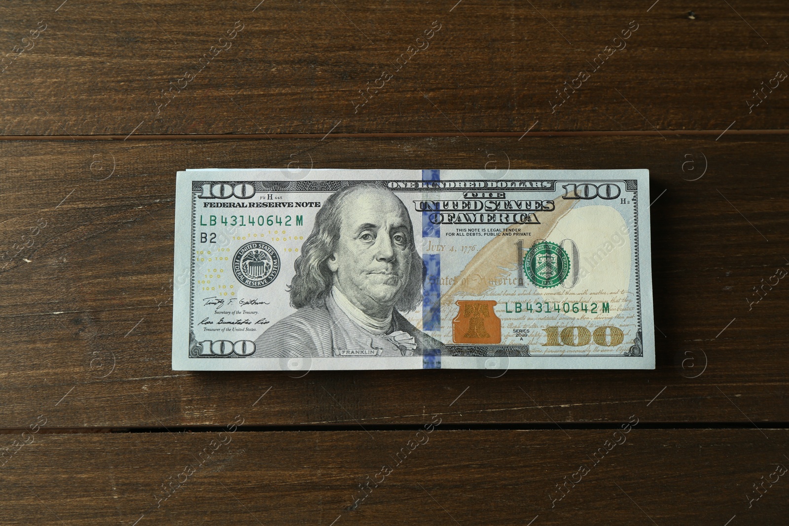 Photo of Stack of dollar banknotes on wooden table, top view