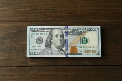 Photo of Stack of dollar banknotes on wooden table, top view