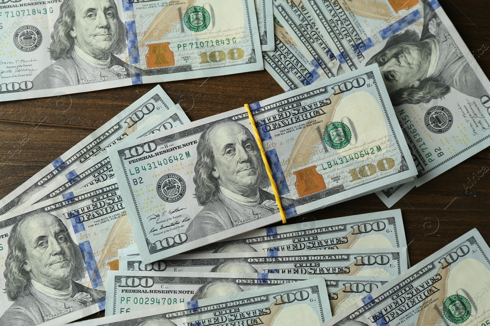 Photo of Many dollar banknotes on wooden table, top view