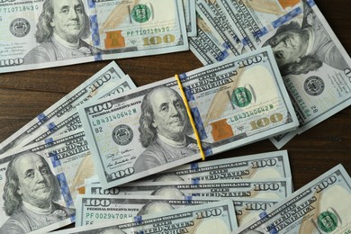 Photo of Many dollar banknotes on wooden table, top view