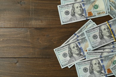 Photo of Many dollar banknotes on wooden table, top view. Space for text