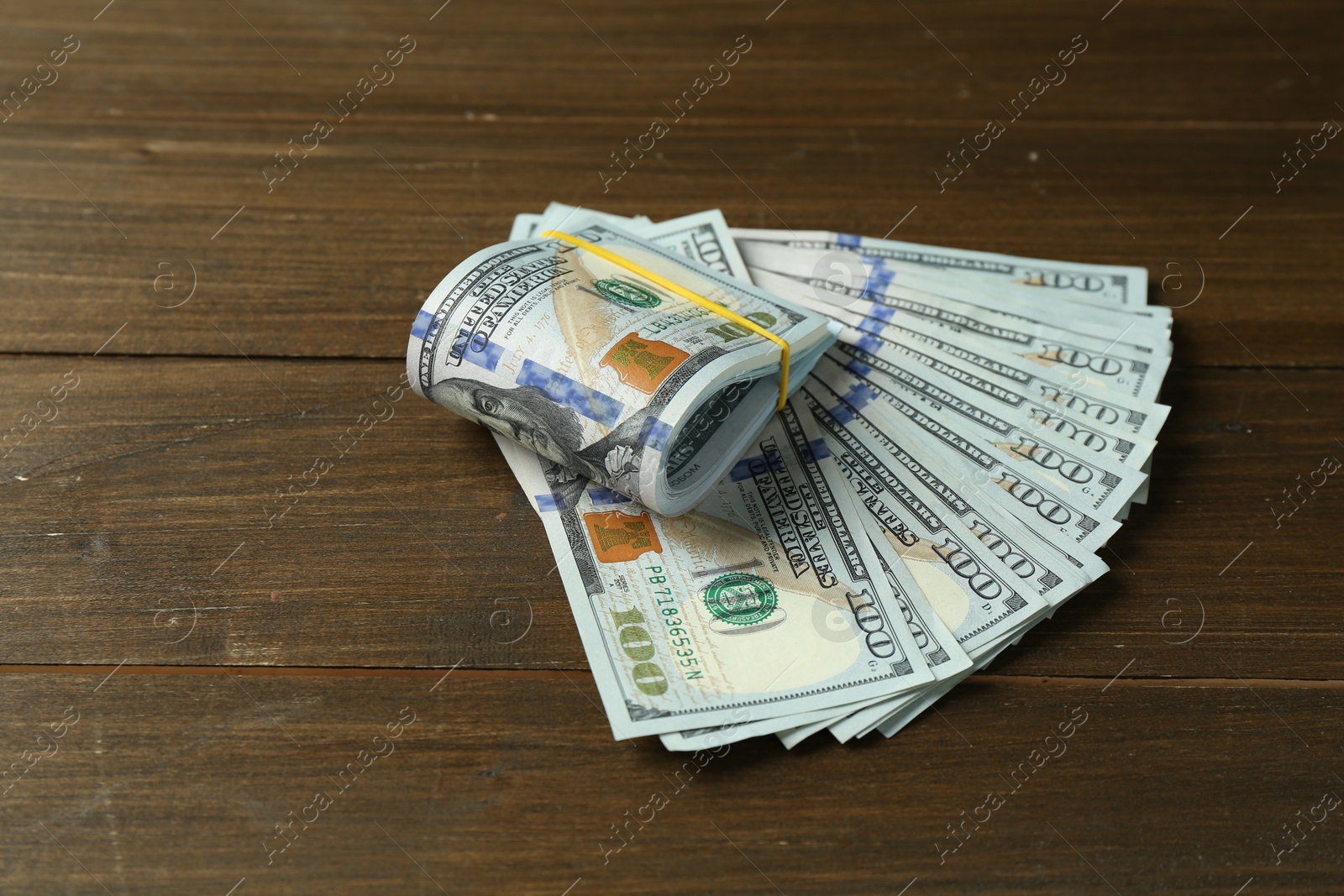 Photo of Many dollar banknotes on wooden table, space for text