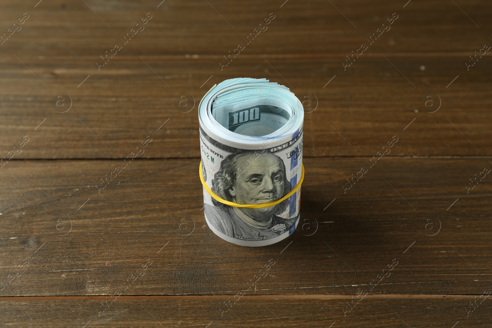 Photo of Roll of dollar banknotes on wooden table