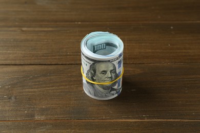 Photo of Roll of dollar banknotes on wooden table