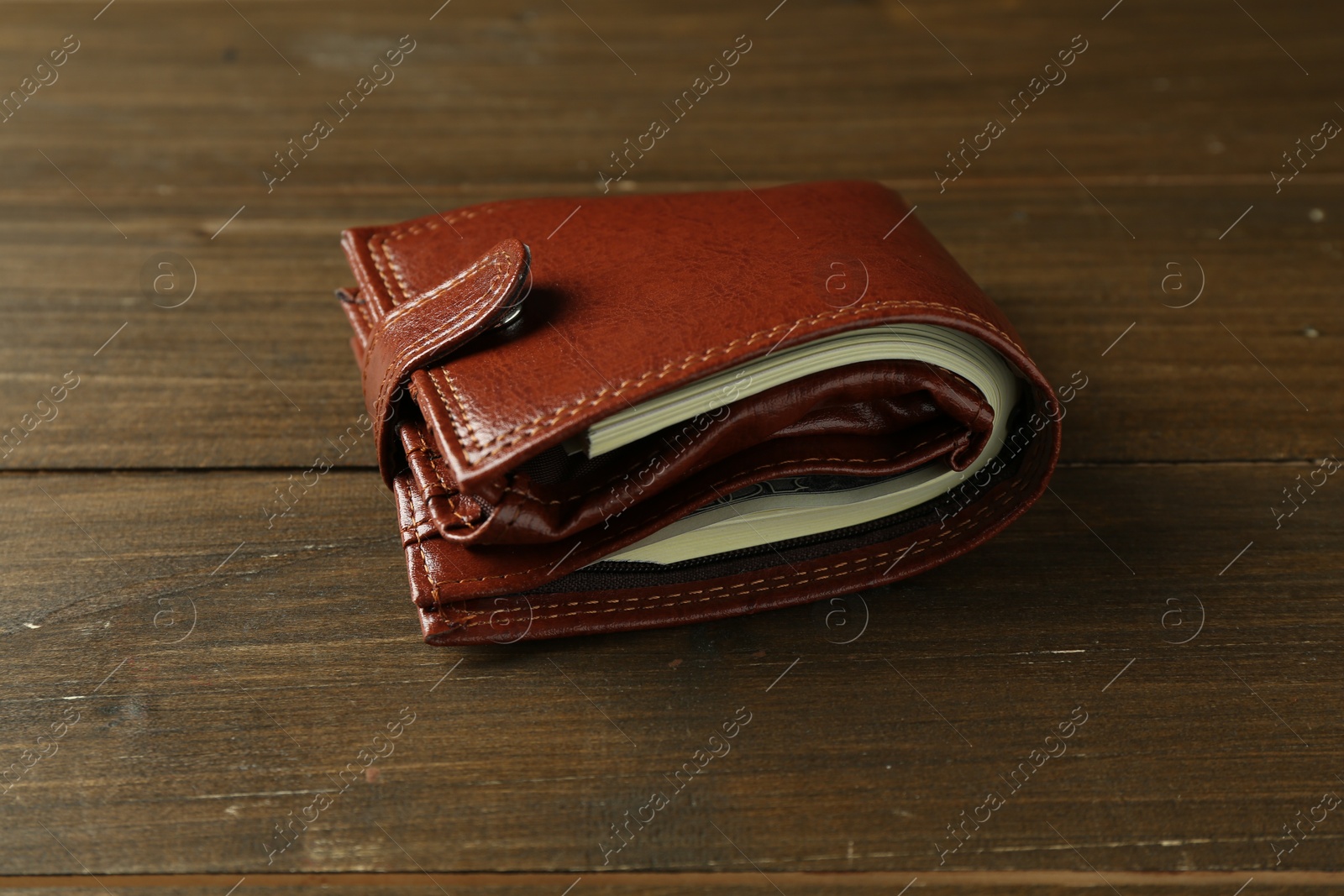 Photo of Leather wallet with dollar banknotes on wooden table, closeup