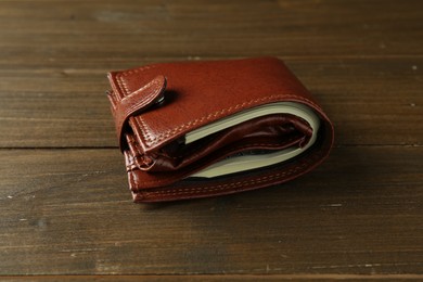 Photo of Leather wallet with dollar banknotes on wooden table, closeup