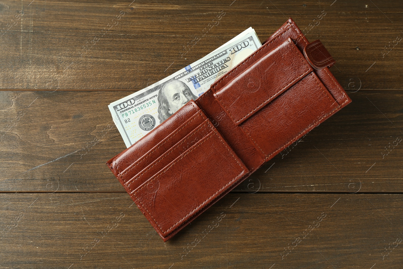 Photo of Leather wallet with dollar banknotes on wooden table, top view