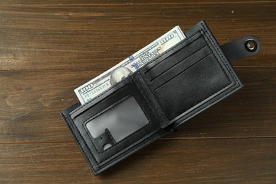 Photo of Leather wallet with dollar banknotes on wooden table, top view