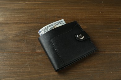 Leather wallet with dollar banknotes on wooden table