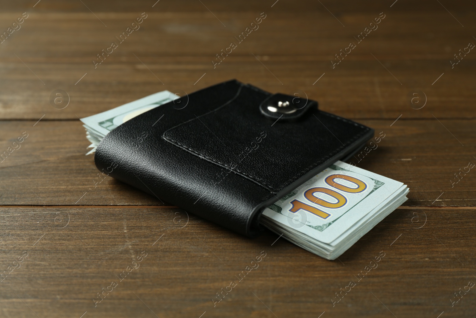 Photo of Leather wallet with dollar banknotes on wooden table