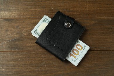 Photo of Leather wallet with dollar banknotes on wooden table, top view