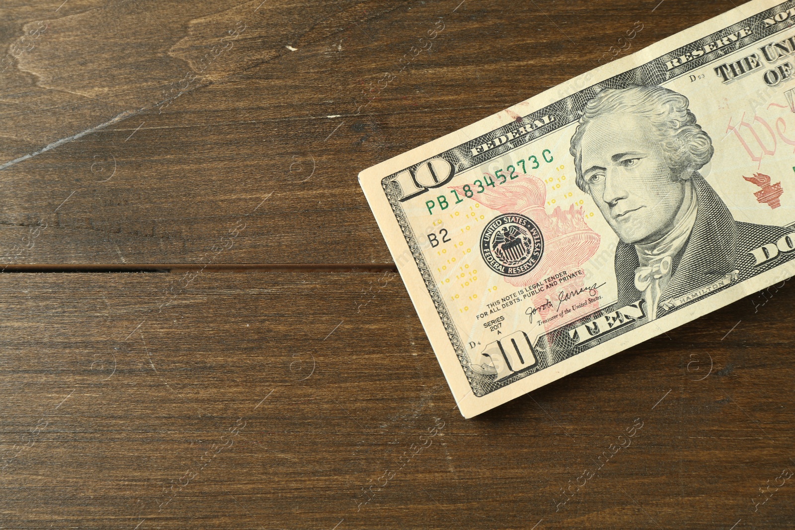 Photo of Stack of dollar banknotes on wooden table, top view. Space for text