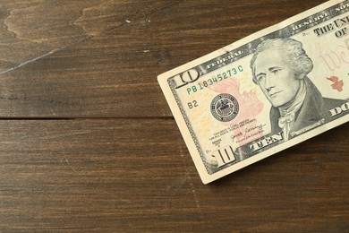 Stack of dollar banknotes on wooden table, top view. Space for text