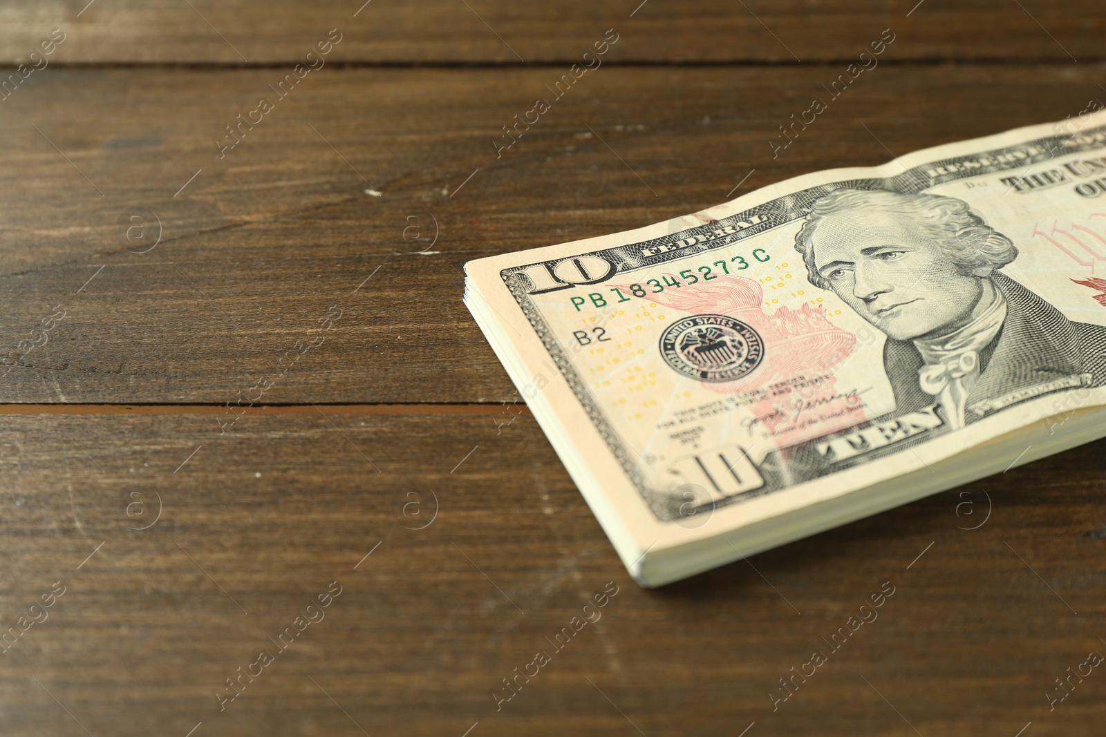 Photo of Stack of dollar banknotes on wooden table, closeup. Space for text